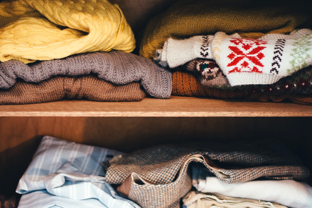 woollen jumpers folded messily on shelf